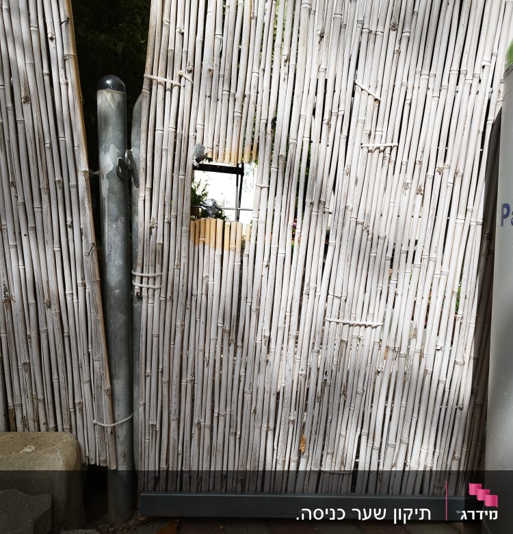 גדר במבוק עם חור קטן ועמוד מתכת בצד